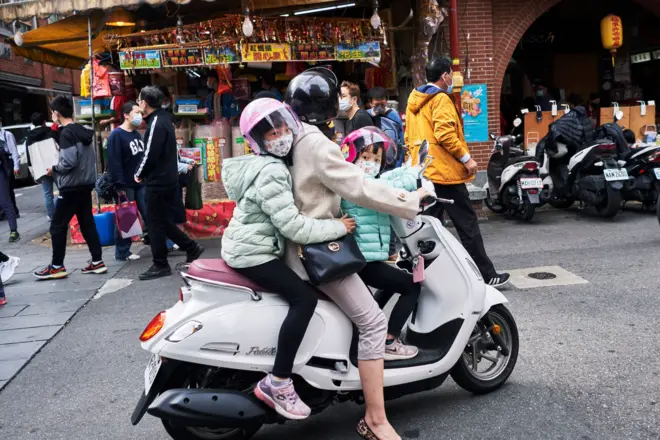 台北一位母亲骑摩托车载着两名子女