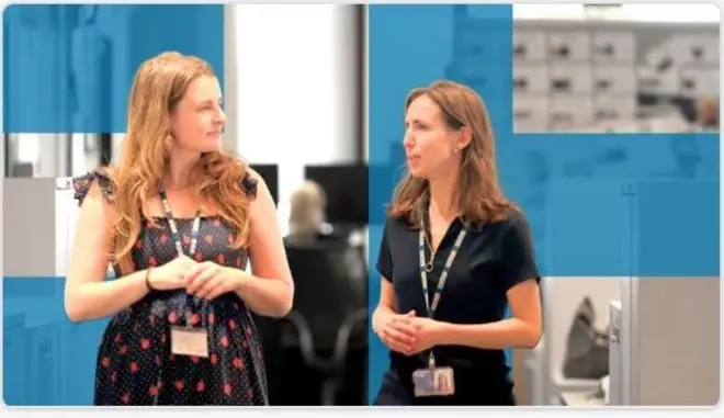 Two female colleagues walk together in conversation.