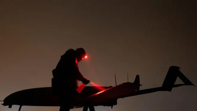 Ночь. Военный освещает налобным фонариком дрон