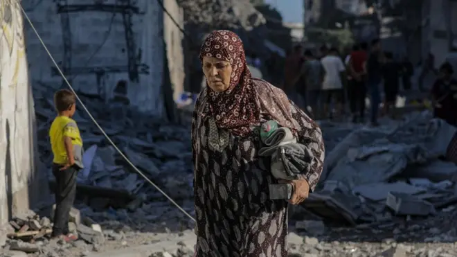 uma idosa palestina andando pelas ruínas de Gaza