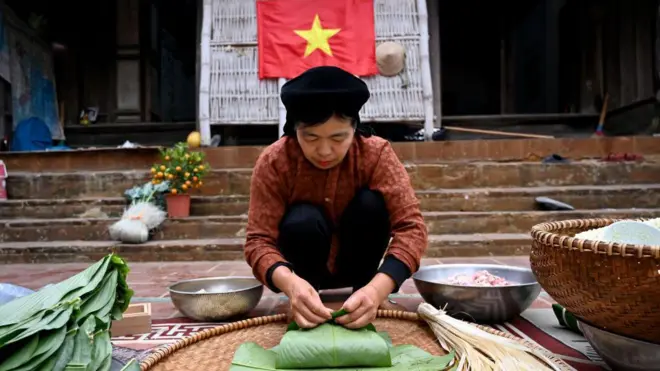 这张摄于2025年1月23日的照片显示，阮氏翠红（Nguyen Thi Thuy Hong）正在其河内郊区家中的院子里包裹“粽子”（Banh Chung），这是一种传统的越南农历新年（春节）美食。以糯米、绿豆和五花肉包裹制成的粽子，几个世纪以来一直是为迎接春节在家中热烈准备的多种菜肴之一。