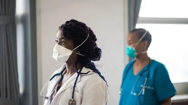 Black women dey wear face mask and health case workers clth