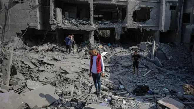 أربعة فلسطينيين يقفون فوق مبان مدمرة في غزة بحثاً عن جثث وناجين.