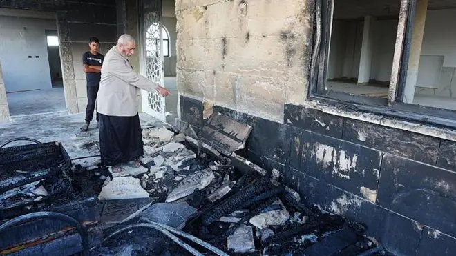 A view of the destruction on the exterior walls of Al-Rahmah Mosque as a Palestinian man points at damage