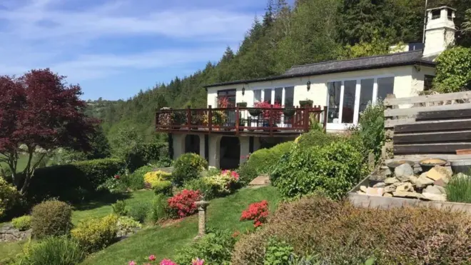 Llidiart y Coed ni jumba jeupe lenye varanda inayovutia kwa vilima na bustani iliyotunzwa vizuri.