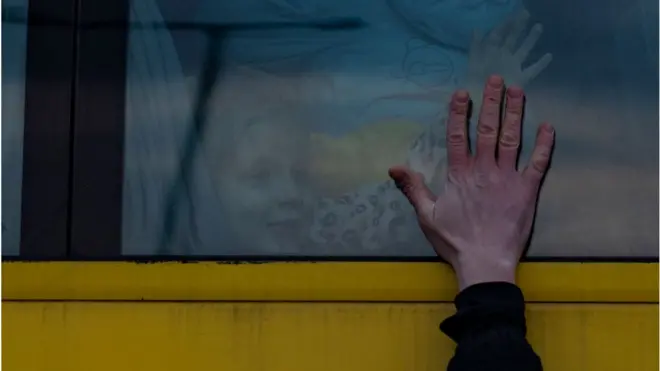 एक पिता यूक्रेन छोड़कर पोलैंड जाने के लिए बस में सवार अपने बच्चे को अलविदा कहता हुआ