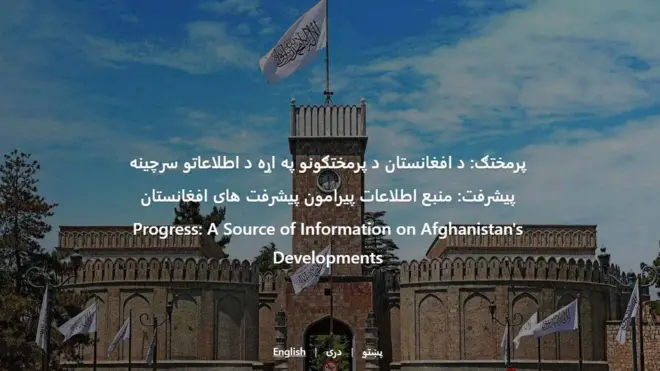 د پرمختګ وېبپاڼې عکس چې په پښتو، دري او انګرېزۍ ژبه پرې لیکل شوي "پرمختګ: د افغانستان د پرمختګونو په اړه د اطلاعاتو سرچینه) تر شا یې د ارګ ماڼۍ او پرې د پاسه د طالبانو سپين بېرغ ښکاري.