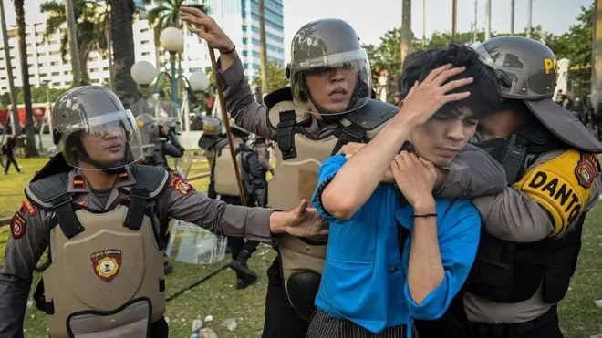 Sejumlah aparat mengamankan seorang pengunjuk rasa yang masuk ke dalam kompleks Parlemen, Senayan, Jakarta, Kamis (22/08).