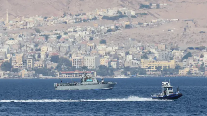 صورة تظهر سفناً حربية وتظهر خلفها مبان على الساحل 