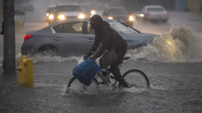 Hombre en bicicleta en medio de un aguacero
