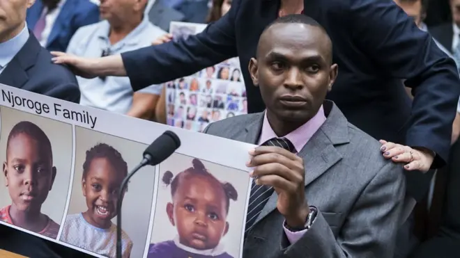 (Photo: Paul Njoroge holds up a picture of his three children. Credit: Getty Images)