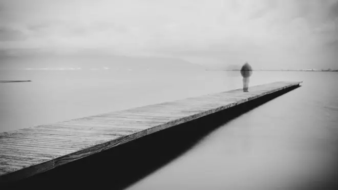 Una mujer camina hacia el final de un muelle