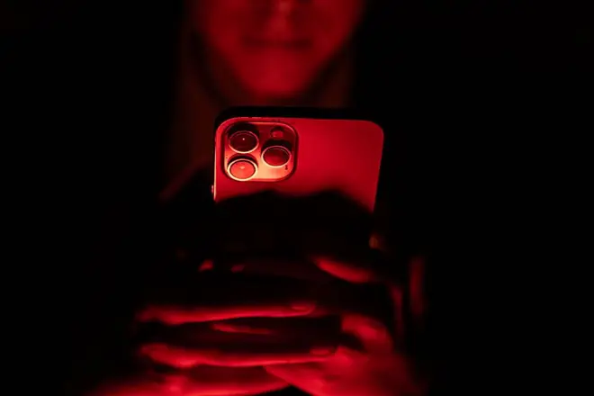 Jovem usando celular no escuro