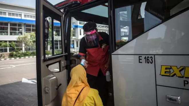 Seorang calon penumpang diperiksa suhu tubuhnya oleh awak bus di sebuah terminal bus di Surabaya, Jawa Timur, Selasa (09/06).