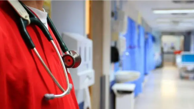 Onye dọkịta yi uwe na-acha ọbara ọbara na nyara igwe e ji enyocha obi mmadụ n'olu.