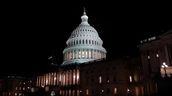 暗い夜空を背に、建物内の一部に明かりがついた米連邦議会議事堂