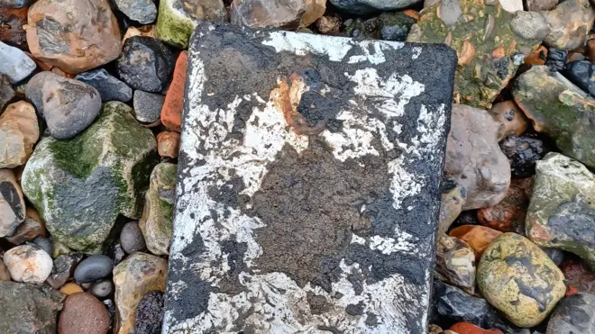 O iPad mini coberto de lama cercado por pedras depois de ter sido retirado do Rio Tâmisa em novembro de 2024