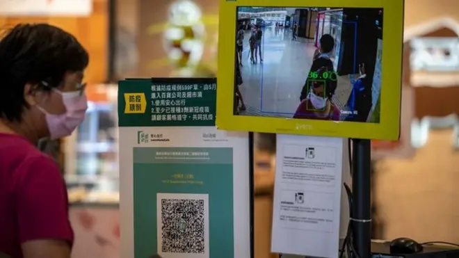 政府推行“疫苗通行证”政策之后，市民需要接种一定数量的疫苗才可以获得通行证，这个通行证对于日常生活工作什至去医院法庭都有一定的影响（图为香港一家购物中心内的商店入口处放置了“安心出行”二维码和温度检测点）。