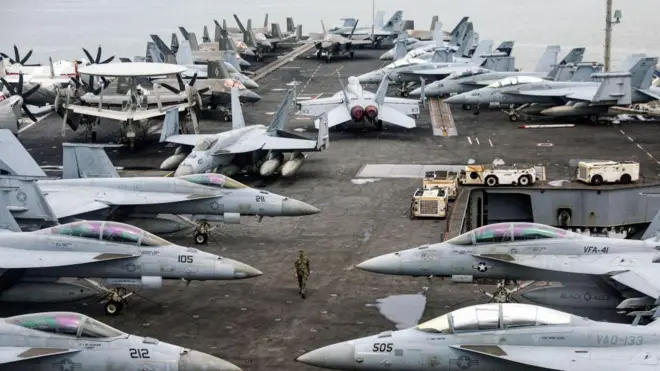 USS Abraham Lincoln uçak gemisinin güvertesinde yer alan onlarca savaş gemisinin arasında yürüyen bir asker