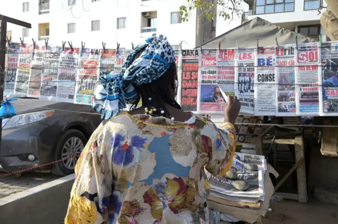 Une femme sénégalaise lit les titres des journaux en vente dans une rue de Dakar le 16 février 2024. 