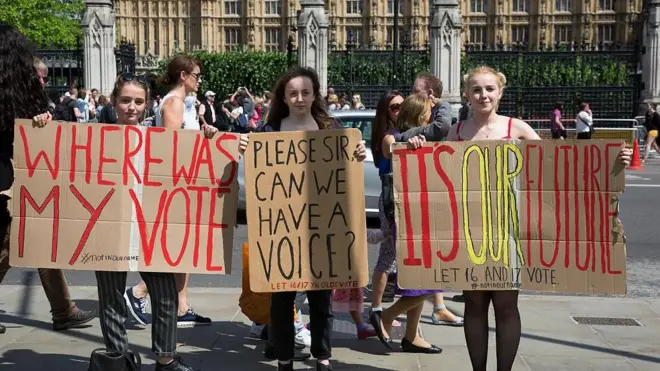 Four young women hold signs calling for votes for 16 year olds