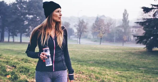 Woman holding coffee walking outside