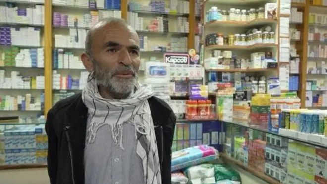 یکی ه از بیماران دارای التهاب روده در داخل یک دواخانه دیده می‌شود او ریش سفید دارد و در پشت سرش قفصه‌های دوا است 