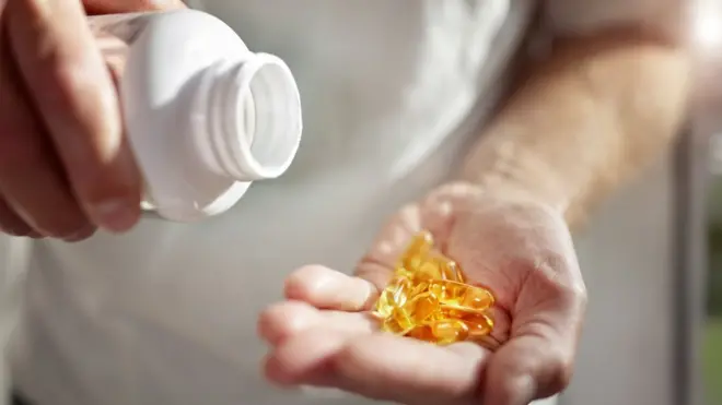 A man with fish oil tablets in his hand