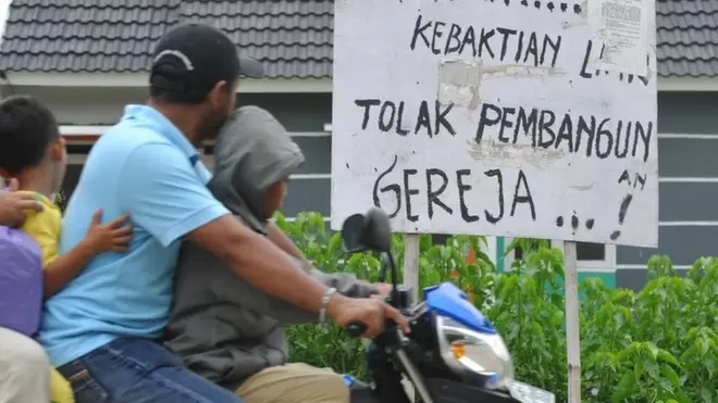 Penduduk di Bekasi melewati tulisan tolak pembangunan gereja di dekat GPIB Filadelfia, Bekasi, yang disegel pada 25 Desember 2012.