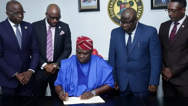 Awọoran Ambode lasiko ti o n tọwọ bọ iwe
