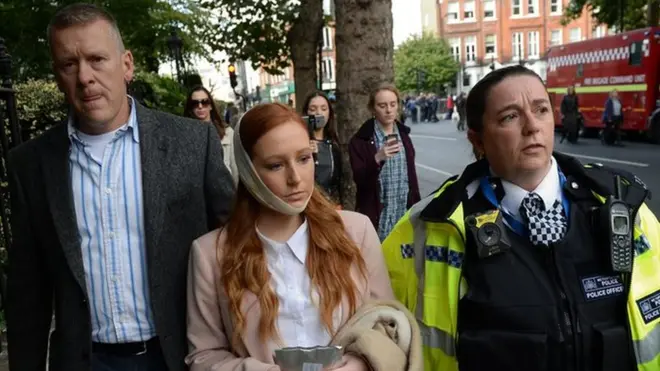 救护人员说，许多人受伤，但是并没有人受重伤。图中警察陪同一名受伤者离开现场。