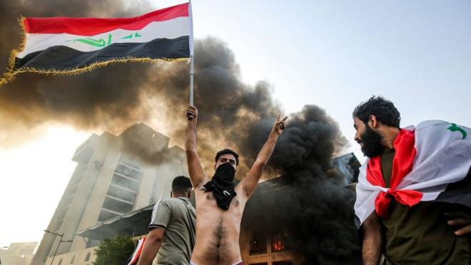 Протестующий, раздетый по пояс и с флагом Ирака