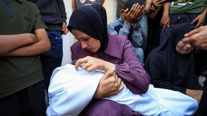 Una mujer acunando a su hijo muerto.