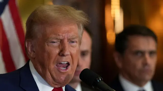 Трамп у микрофона на фоне флага США