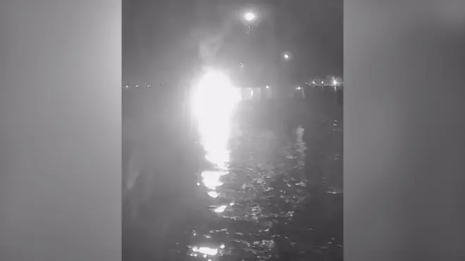 Яркий белый свет на черно-белом снимке указывает на возможную точку взрыва. Очертания судна почти не различимы, но на переднем плане видна вода. Это указывает на то, что фотография сделана с другого судна. 