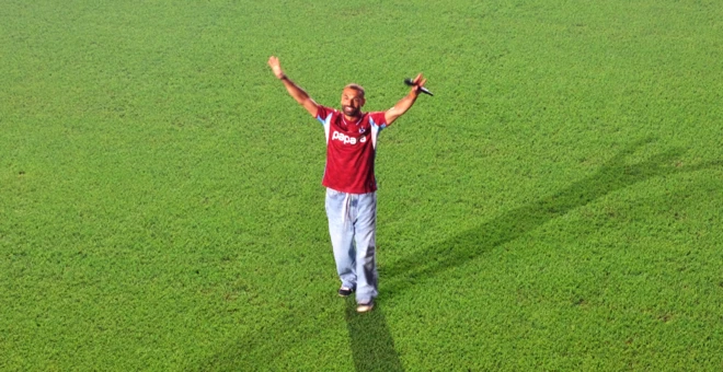 Salah isimli oyuncu üzerinde tranzonspor forması, altında kotla taraftarı selamlyor. Bu açıdan yalnızca sahanın çimleri ve o görünüyor.
