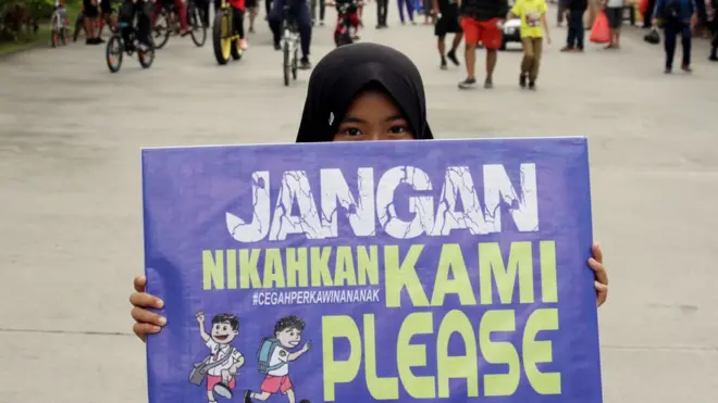 Seorang anak membawa poster saat aksi peringatan Hari Perempuan Internasional di Makassar, Sulawesi Selatan, Minggu (8/3). Aksi tersebut untuk mensosialisasikan pencegahan perkawinan anak guna menekan angka perkawinan usia dini yang masih marak terjadi.