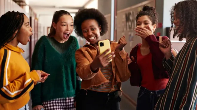 چند نوجوان دور هم جمع هستند و به گوشی تلفن یک نفر نگاه میکنند و میخندند