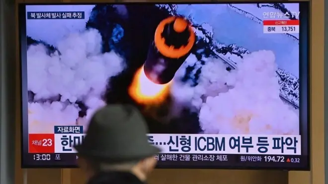 People watch a television screen showing a news broadcast with file footage of a North Korean missile test, at a railway station in Seoul on March 16, 2022