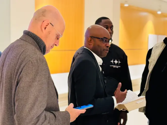 Charles Onana afashe igitabo mu ntoke na Damien Sirieix ariko araraba terefone i Paris, ku wa 11 Gitugutu 2024