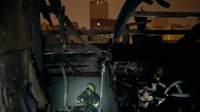 یک مأمور امداد و نجات با استفاده از چراغ قوه در حال جستجو در میان آوارهای برجای مانده از حملات موشکی تازه روسیه در کی‌یف 