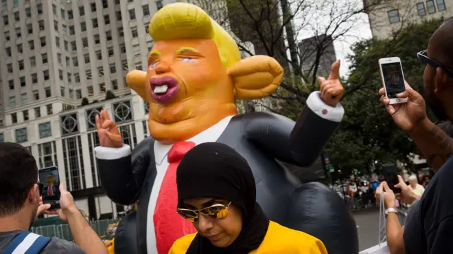 Pedestrians stop and take photos of a 15-foot tall inflatable rat in the likeness of U.S. President Donald Trump at the corner of Fifth Avenue and 59th Street up the road from Trump Tower, August 14, 2017 in New York City.