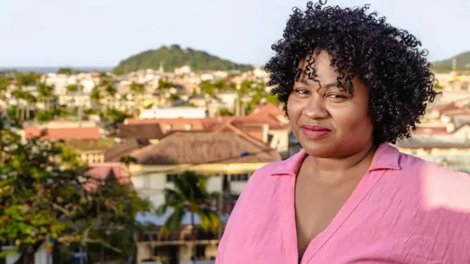 Imagembaixar o betnacionaluma mulher negra, blusa rosa, com cidade ao fundo