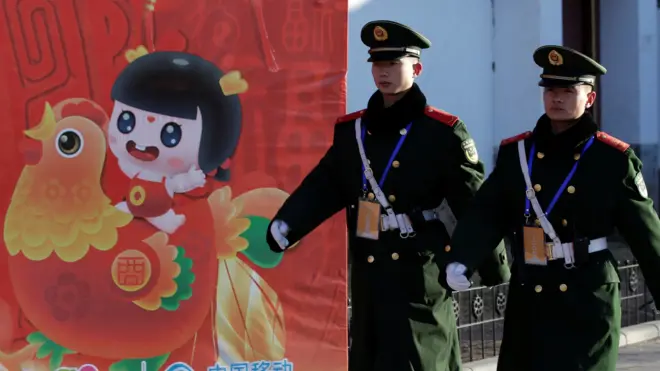 北京大观园公园内一幅庆祝鸡年春节的广告画前两名武警在巡逻(30/1/2017)