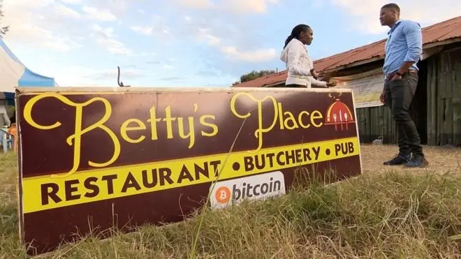 Beatrice Wambugu tenant l'affiche de son restaurant