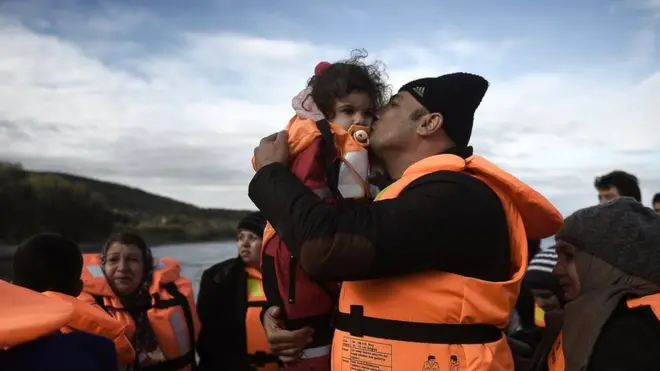 A man kisses a girls as refugees and migrants arrive on the Greek island of Lesbos in December 2015