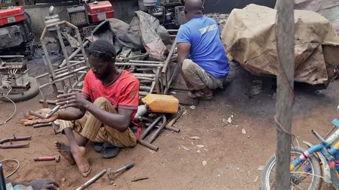 Foto of men wey dey live wit disability dey work for workshop wia dem dey repair and make tricycles