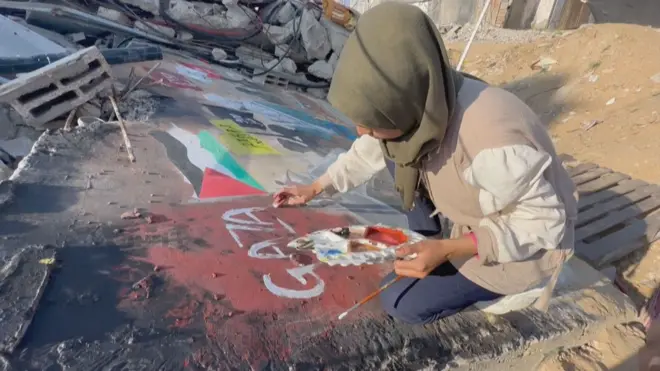 الفنانة أمل أبو الصباح ترسم على أنقاض منزل في غزة