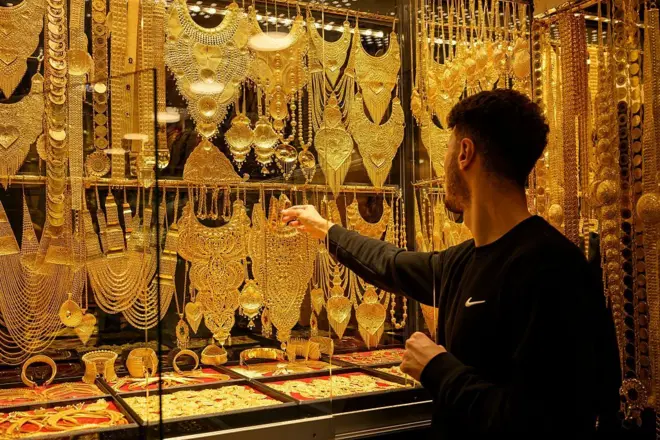 Salesperson displays gold bracelets and necklaces for sale in a gold shop