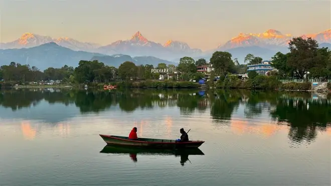 पोखरास्थित फेवातालमा डुङ्गा र पृष्ठभूमिमा हिमाल 